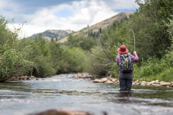 Woman fishing in river at Brush Creek Ranch